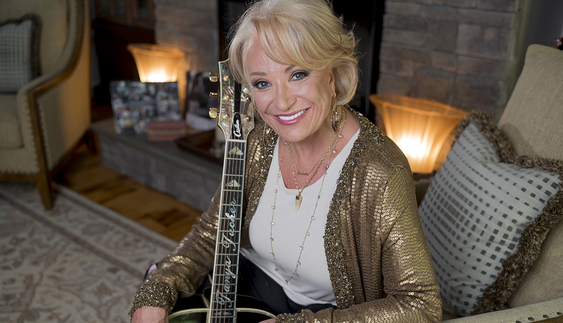 item 3 of Gallery image - Tanya Tucker sitting down holding a guitar. 