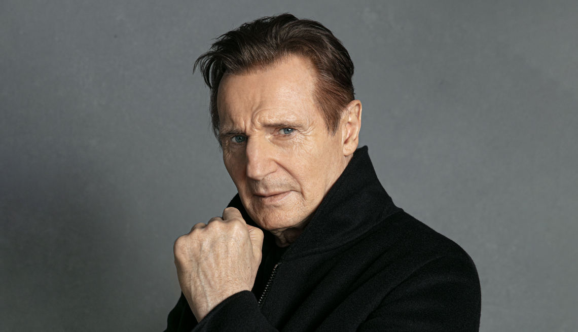 actor liam neeson looking over his shoulder at the camera