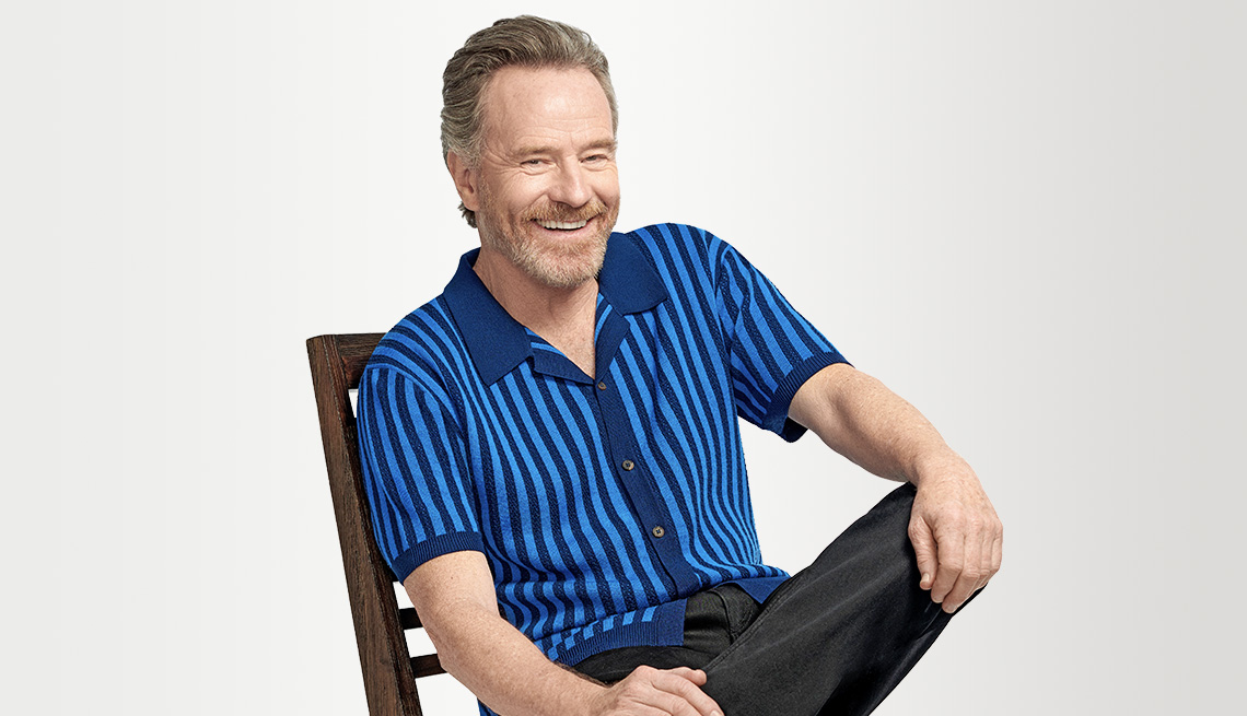 actor bryan cranston sitting in a chair smiling