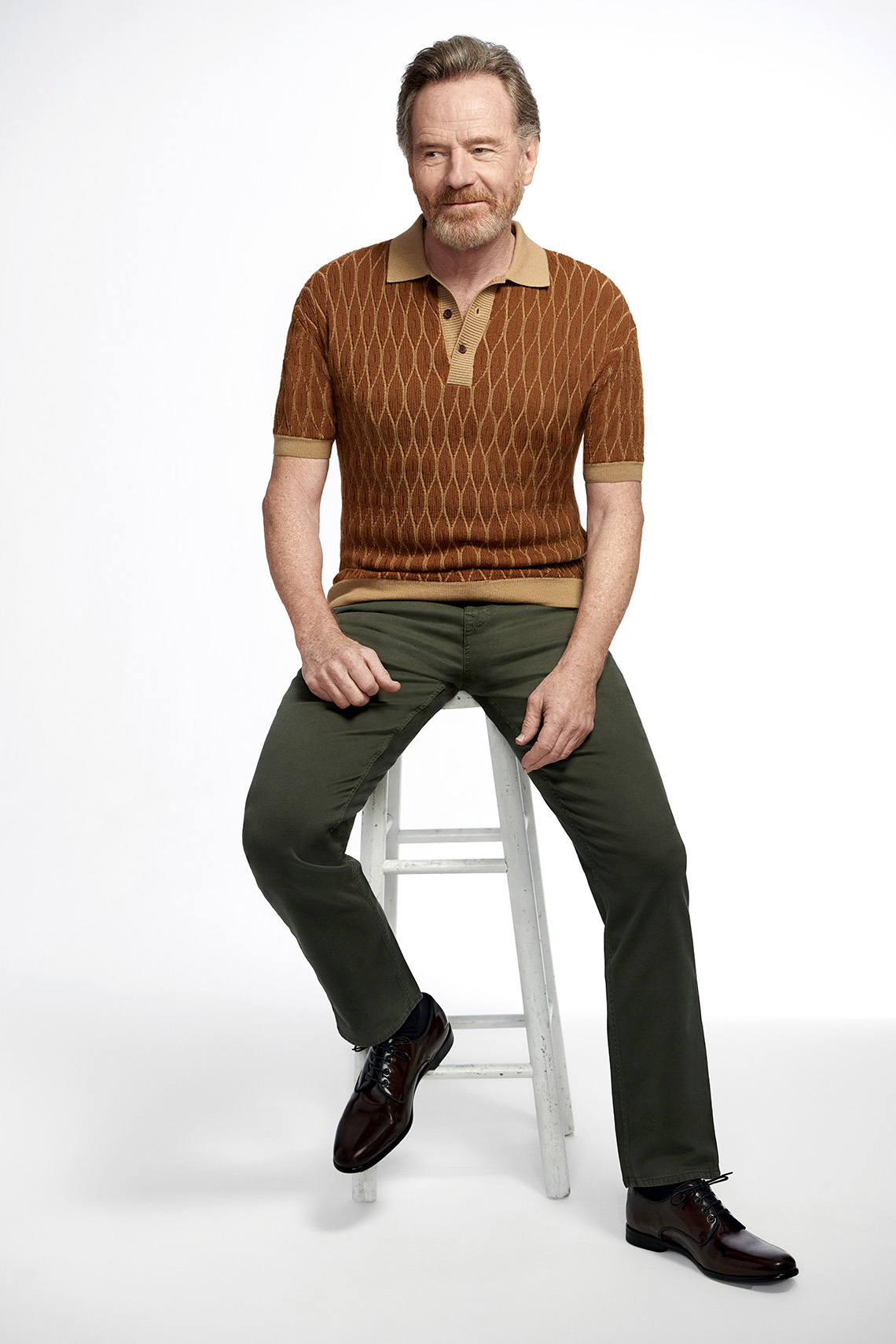 El actor Bryan Cranston sentado en un taburete.