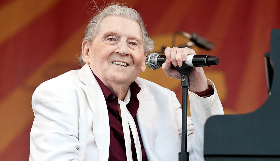 item 3 of Gallery image - Jerry Lee Lewis smiling onstage while placing his left hand on a microphone stand during his performance at Fair Grounds Race Course in New Orleans, Louisiana