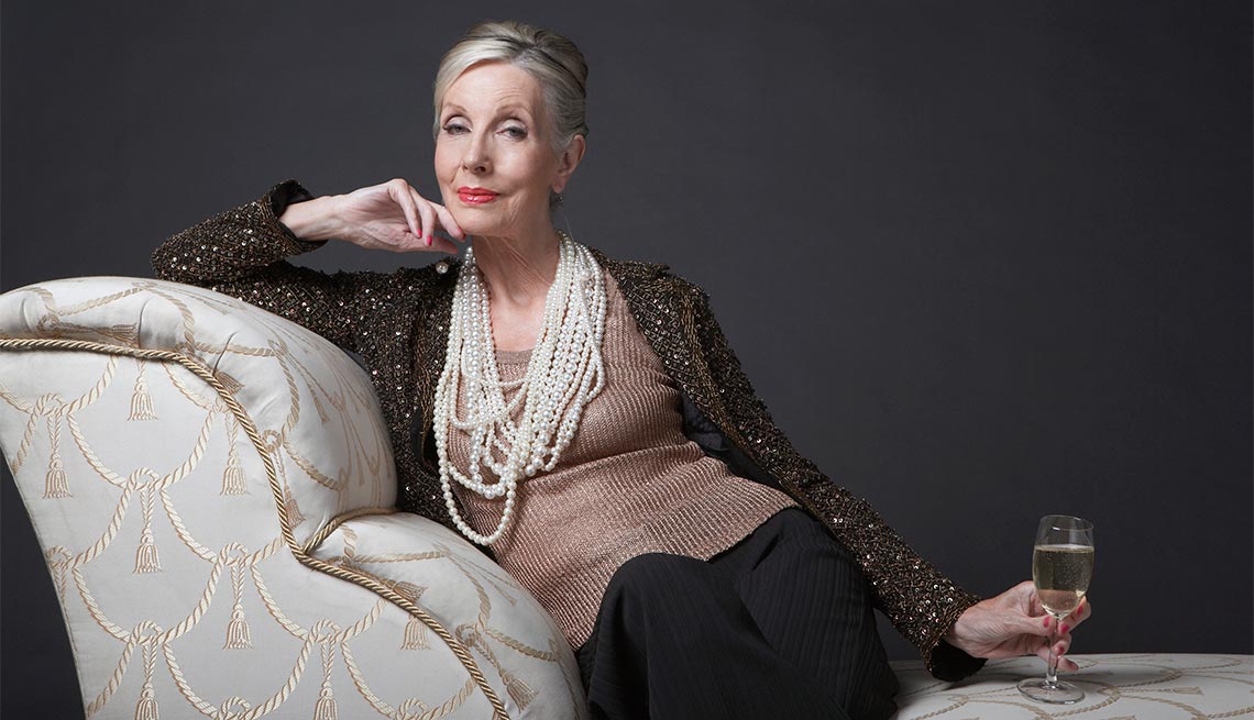 Mujer mayor sentada en un sofá con una copa de vino - Consejos de moda para mayores de 50