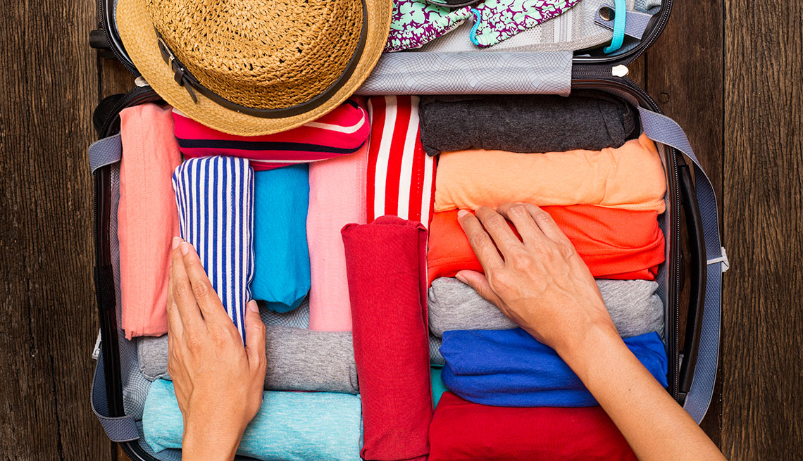 mature woman organizing colorful clothes in a suitcase