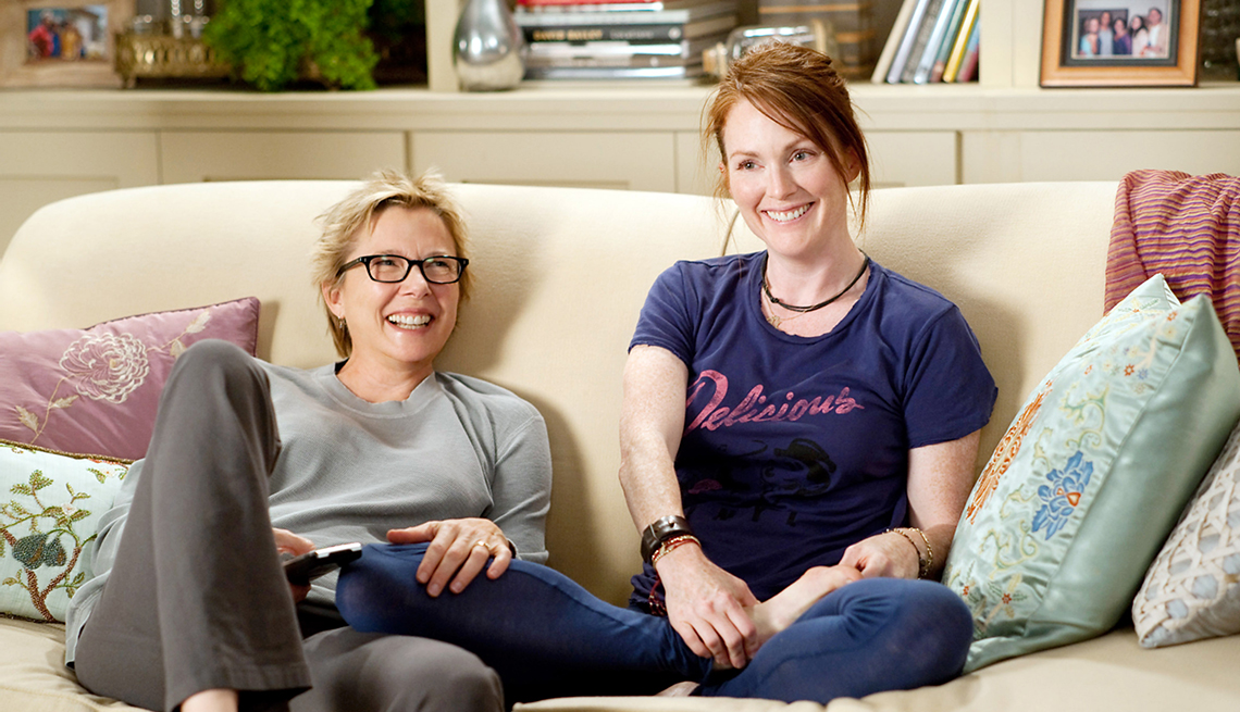 Annette Bening and Julianne Moore sitting on a couch in the film The Kids Are All Right