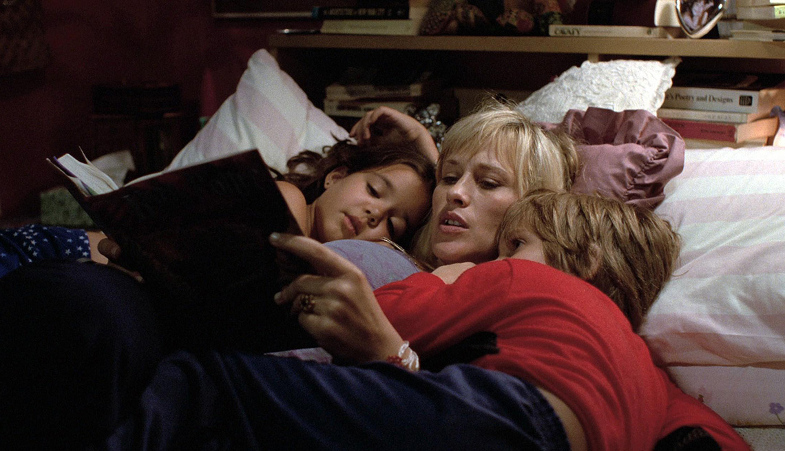 Lorelei Linklater, Patricia Arquette and Ellar Coltrane lying on a bed reading a book in the film Boyhood