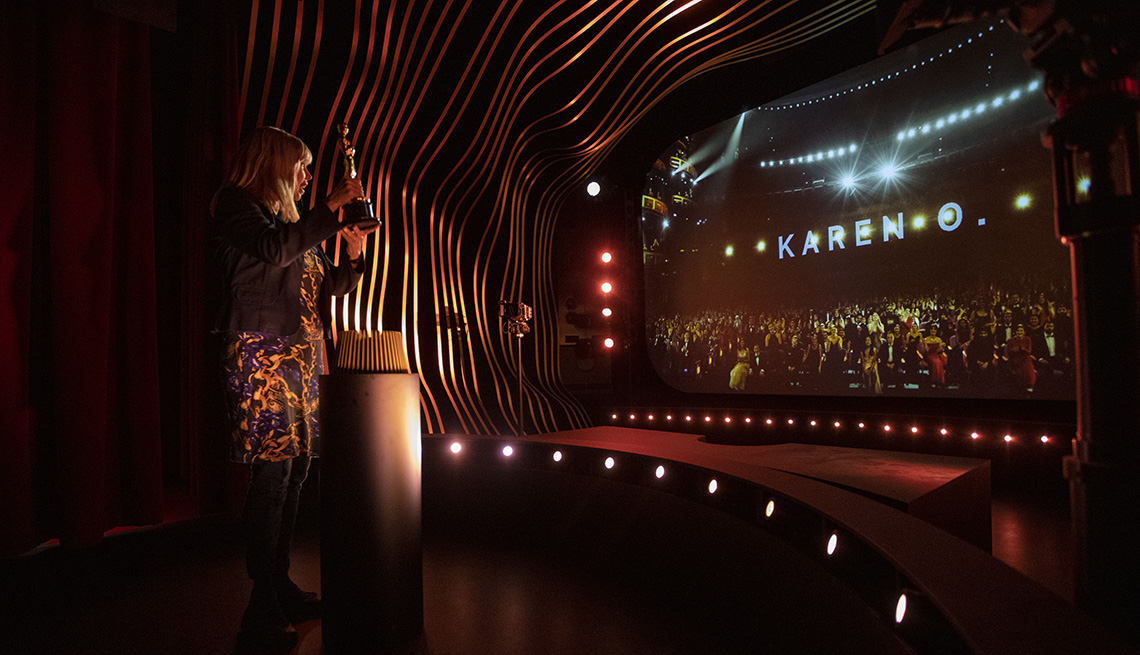 Una mujer sosteniendo un trofeo Oscar en la exposición Oscar Experience del Academy Museum of Motion Pictures.