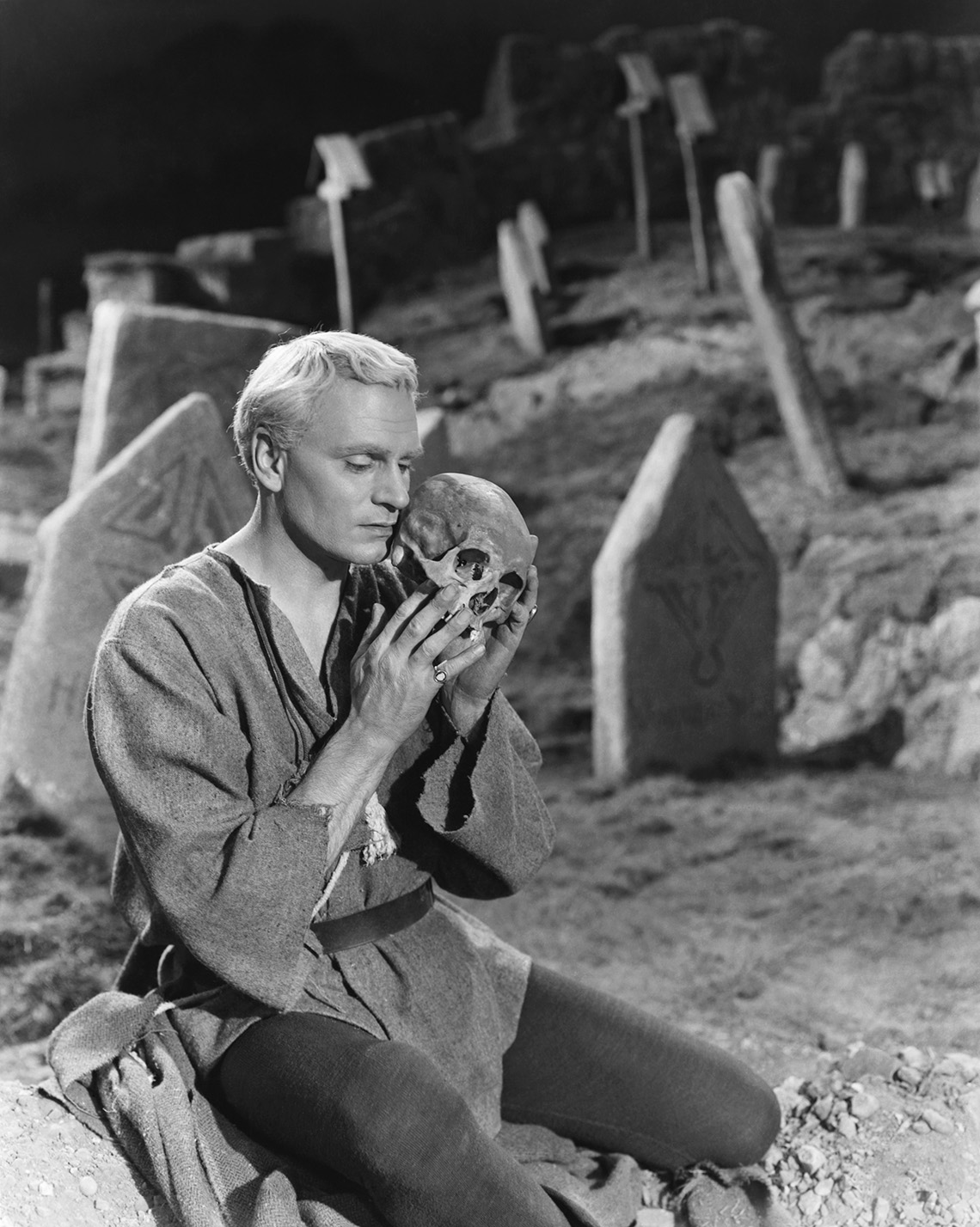 Laurence Olivier sostiene una calavera en un cementerio en una escena de la película "Hamlet".