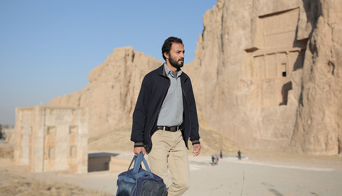 Amir Jadidi holds a blue bag outside in the film A Hero