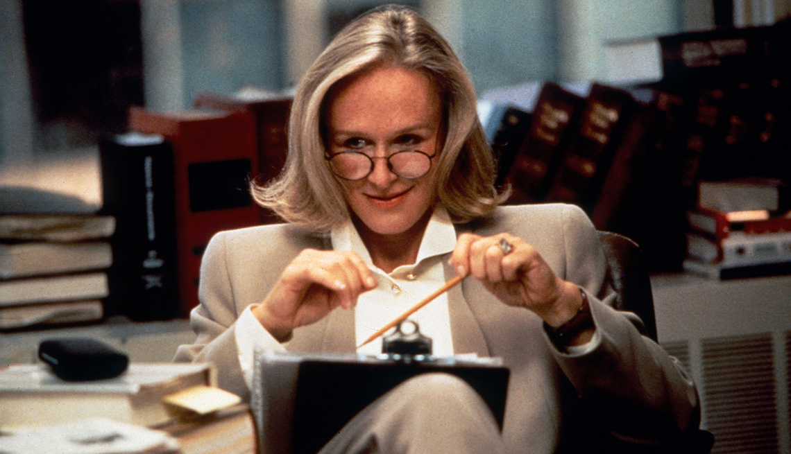 Glenn Close sitting in a chair with a clipboard in her lap while she holds a pencil in the film The Paper