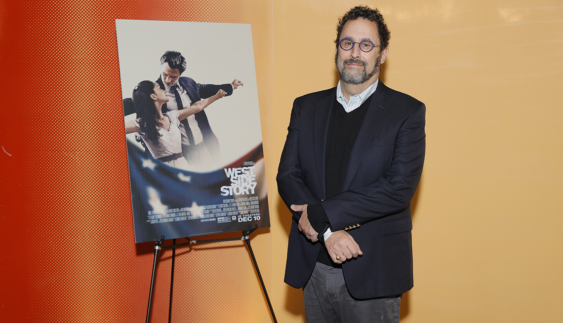 item 9 of Gallery image - El guionista Tony Kushner junto a un cartel promocional de su película "West Side Story".