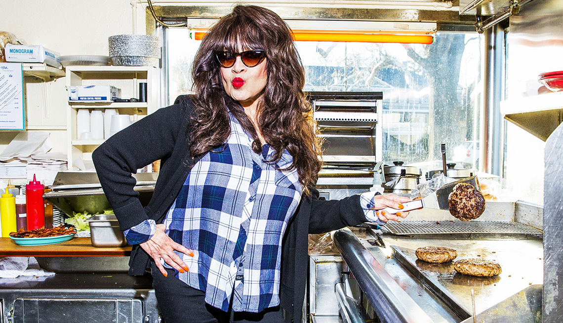 Ronnie Spector in a kitchen flipping burgers.