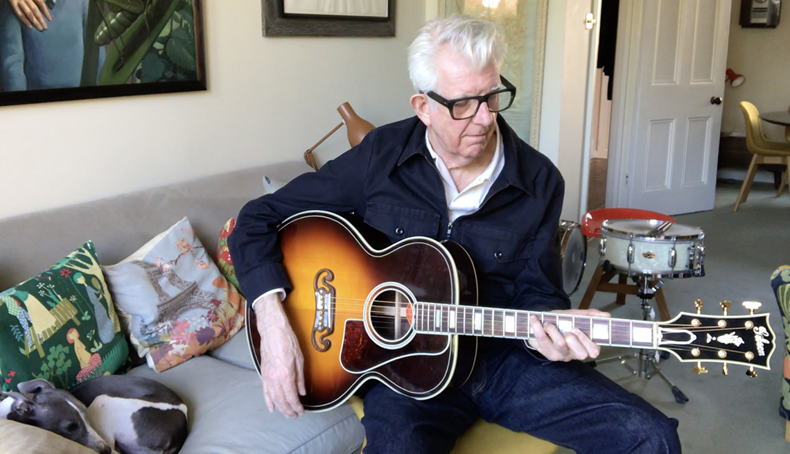 Singer songwriter Nick Lowe playing the guitar at home