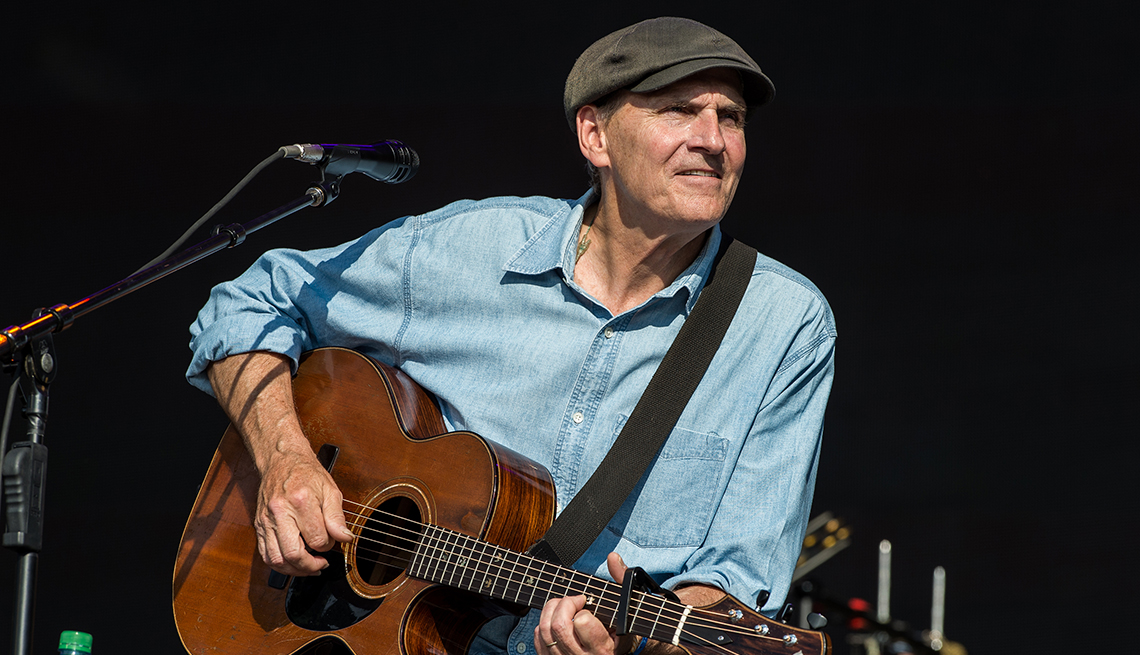 James Taylor performing on stage with his guitar