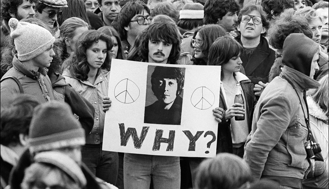 Hombre sosteniendo un cartel que dice, ¿Por qué?, en medio de la vigilia por la muerte de John Lennon, días despues de su asesinato. Nueva York, 1980.