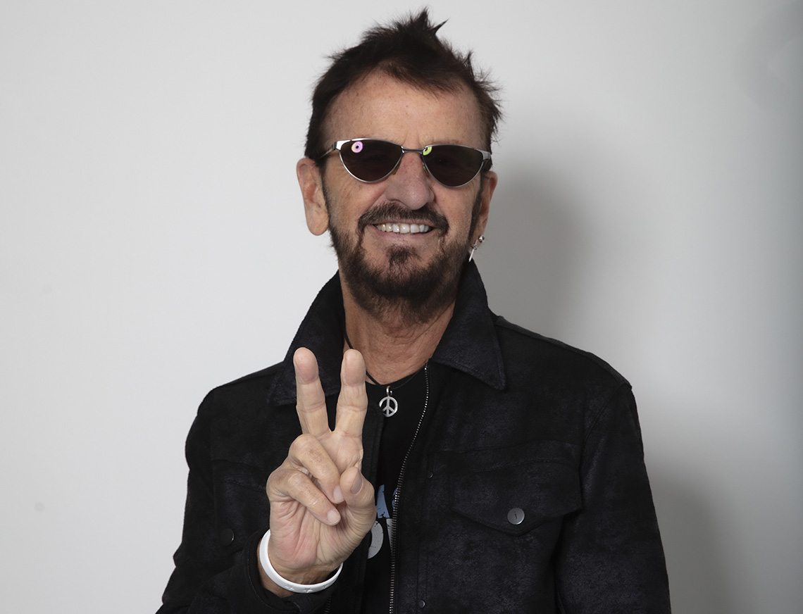 Ringo Starr con gafas de sol mientras da el signo de la paz.
