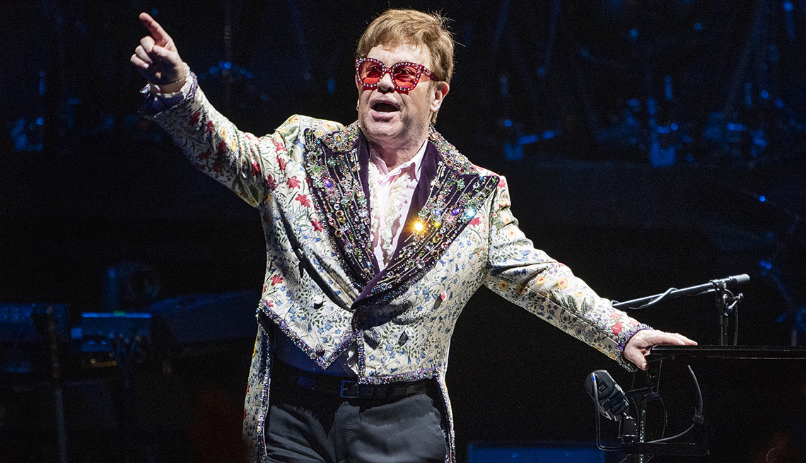 Elton John señala a la multitud en el escenario durante su gira Farewell Yellow Brick Road Tour.
