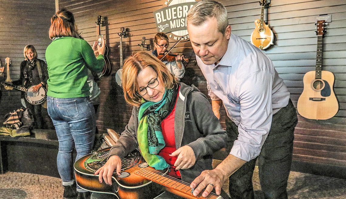 item 10 of Gallery image - man showing woman how to play the dobro at the bluegrass hall of fame museum