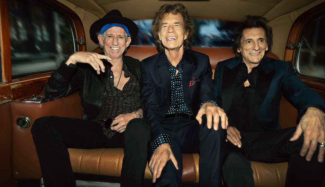 Keith Richards, Mick Jagger y Ronnie Wood de The Rolling Stones sentados dentro de un vehículo.
