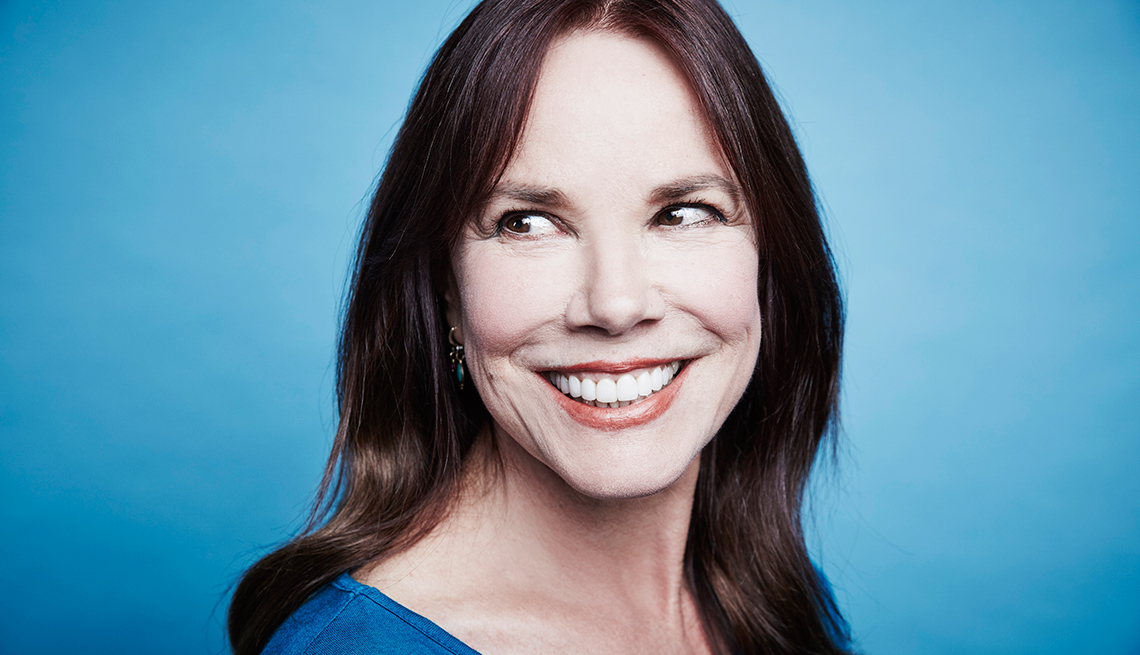 Actress Barbara Hershey smiling for a portrait with a blue backdrop