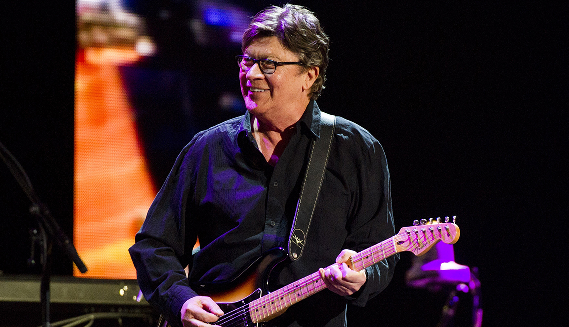 Robbie Robertson on stage holding a guitar 