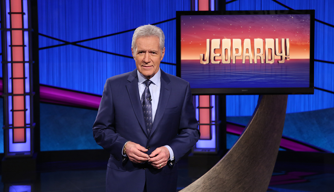 Alex Trebek presentador de Jeopardy frente a un monitor
