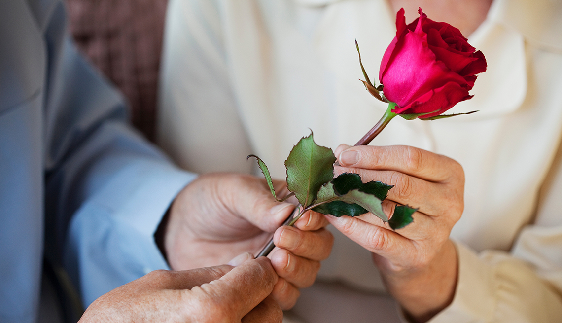 Hombre y mujer sostienen una rosa en sus manos.