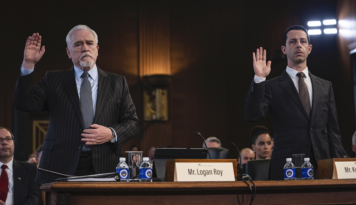 Brian Cox as Logan Roy and Jeremy Strong as Kendall Roy raise their hand in the courtroom in the H B O show Succession