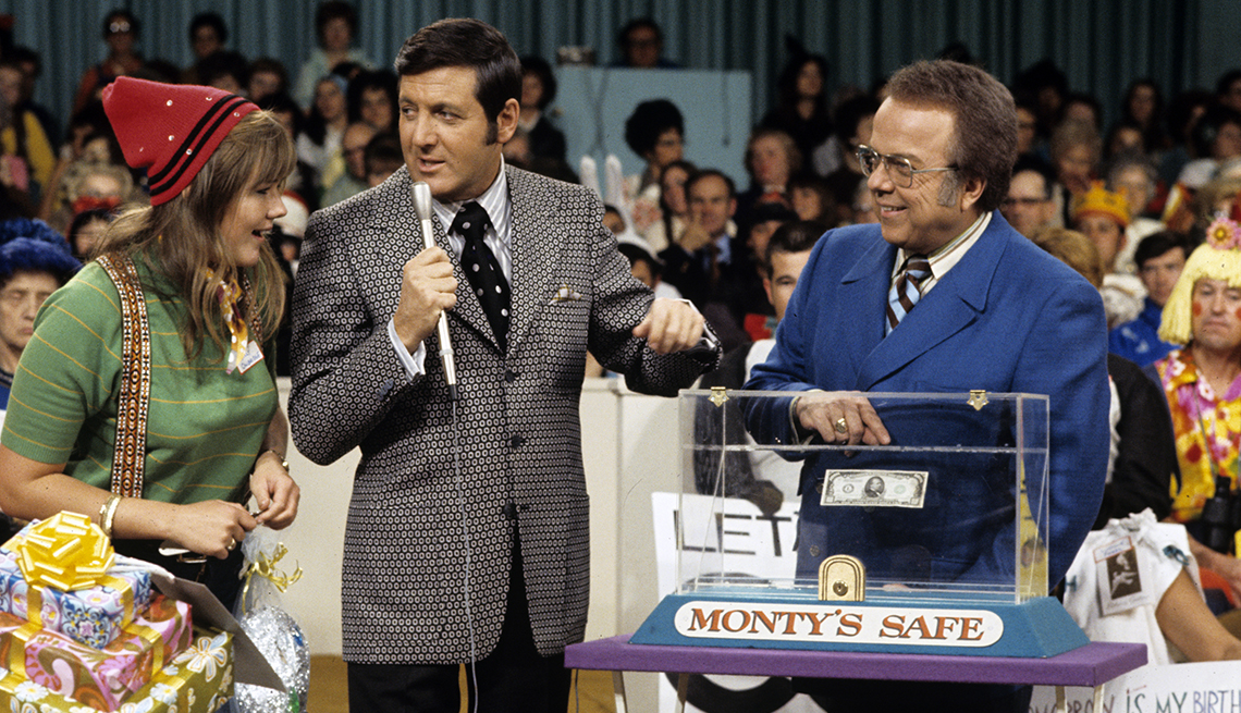 Let's Make a Deal host Monty Hall talks to a contestant as announcer Jay Stewart points to Monty's Safe