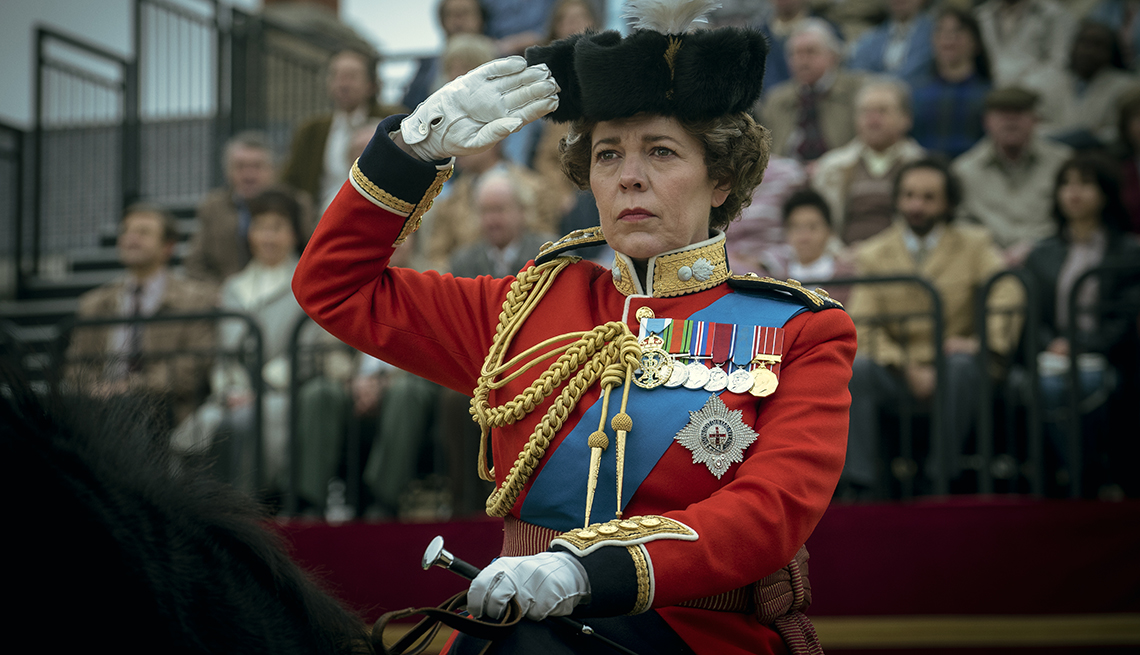 Olivia Coleman, starring as Queen Elizabeth II, gives a salute while riding a horse in a scene from The Crown