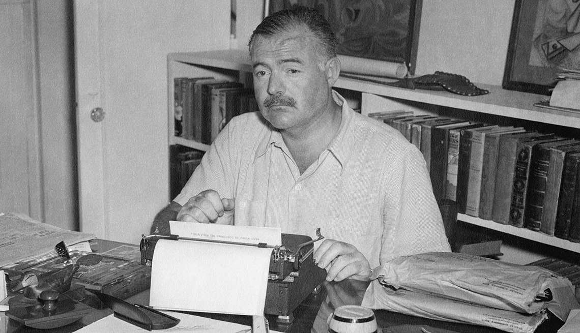 Ernest Hemingway sitting at typewriter at his home in Cuba