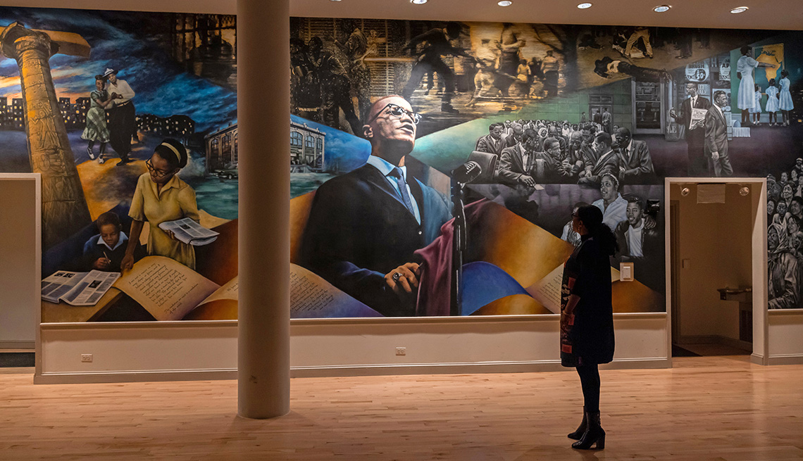 Ilyasah Shabazz stands in front of a mural of Malcolm X and other figures