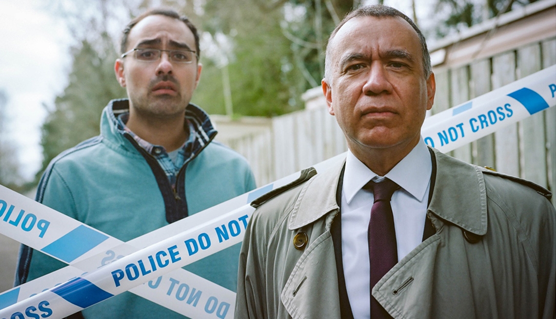 Jamie Demetriou stands behind police tape standing next to Fred Armisen in Documentary Now