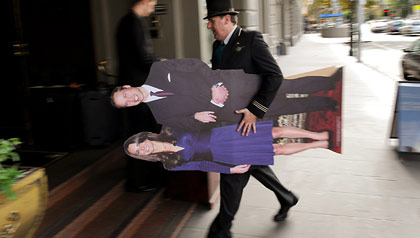 A hotel doorman in Melbourne, Australia, carries a life-size cutout of Prince William and Kate Middleton. 