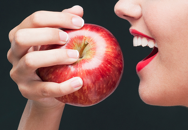 Mujer muerde una manzana roja