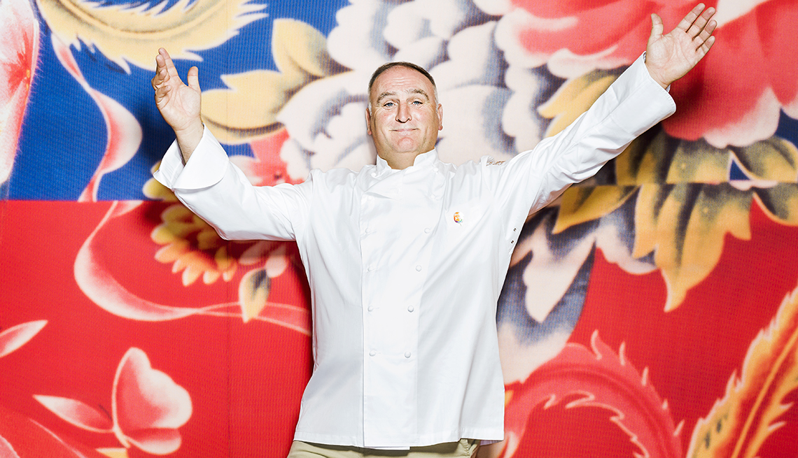 Jose Andres in chef's jacket holding up his hands.