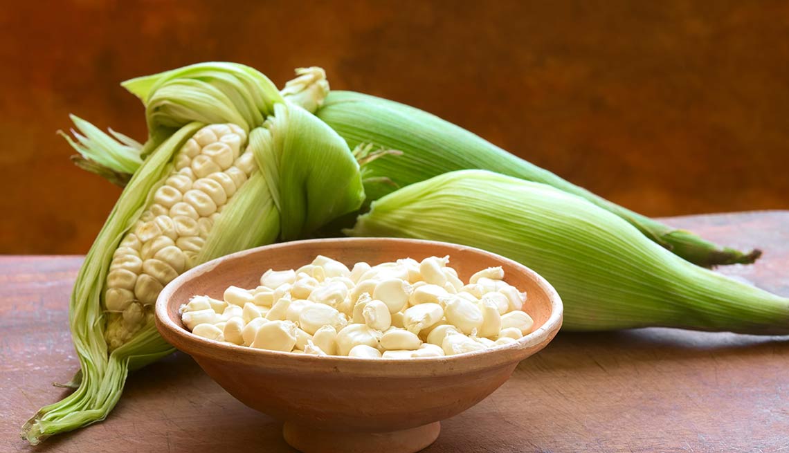 Plato con granos de maíz blanco y maíz enteros envueltos en hoja