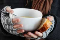 hands holding bread and a bowl of soup