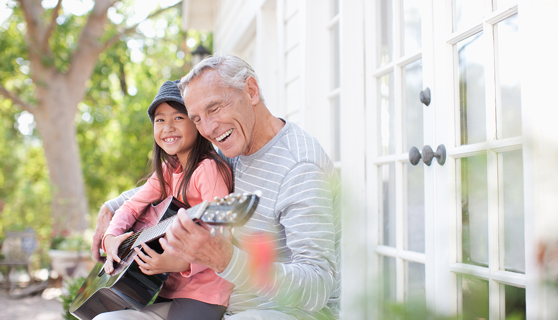 Older man and granddaughter playing guitar