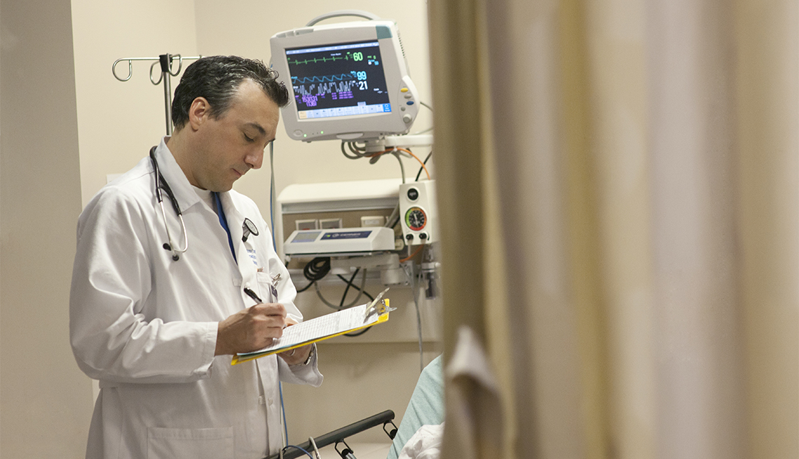 physician writing on clipboard in hospital room