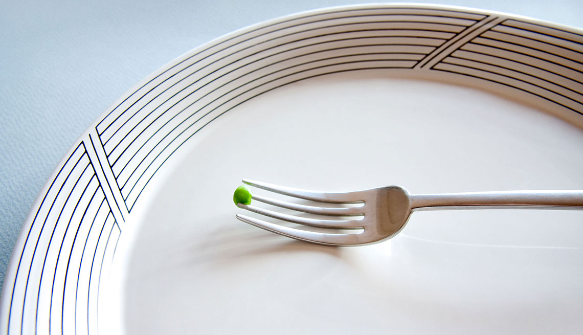one pea on a fork on a white plate
