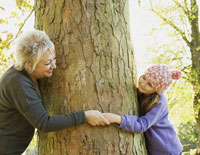 Grandmother and granddaughter (8-9) playing around tree