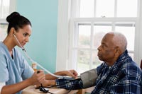 Nurse taking senior man's blood pressure