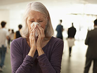 Flu facts- a senior woman blowing her nose