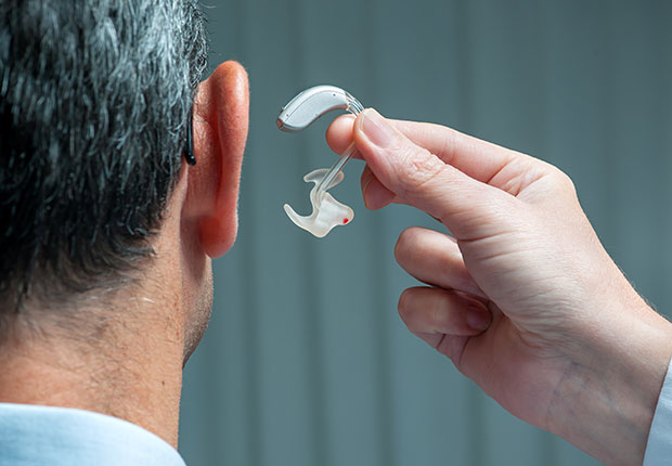 Doctor inserting hearing aid in man's ear, How to Get the Right Hearing Aid: 10 Tips
