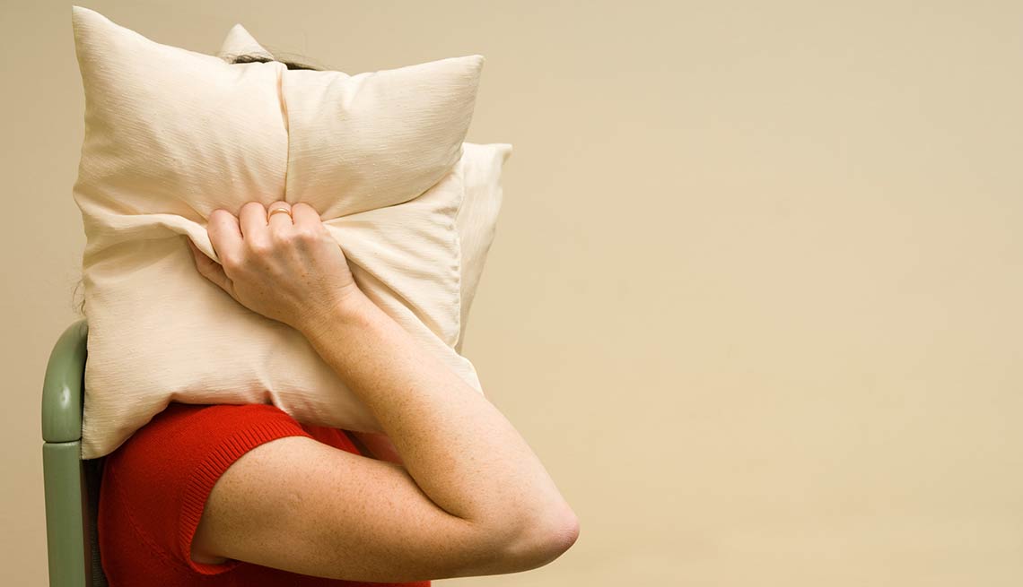 Mujer tapándose los oídos con almohadas