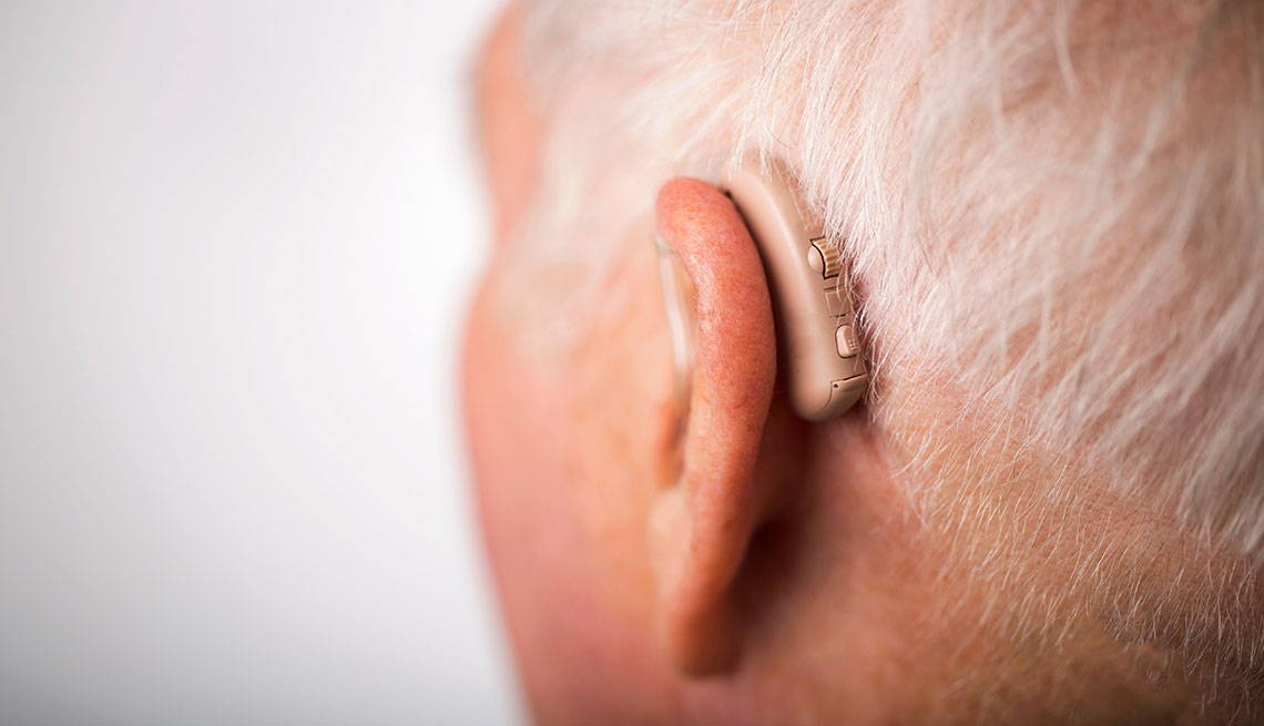 Senior man wearing hearing aid, close up