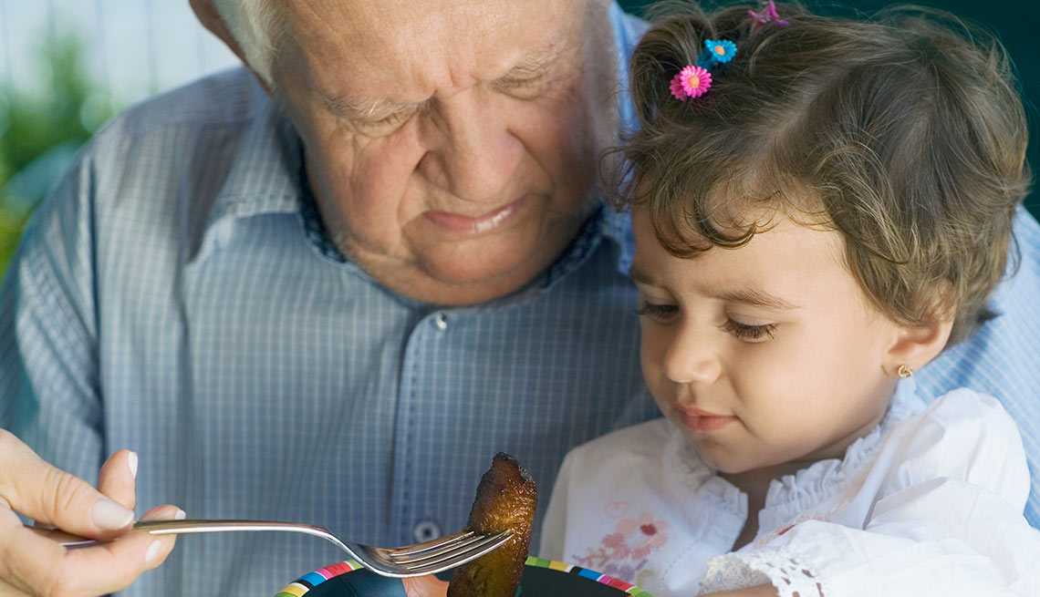 Abuelo dándole de comer a su nieta