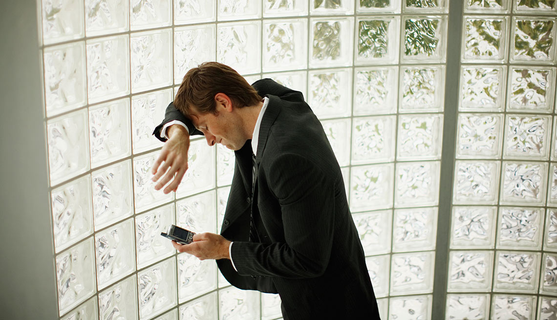 Hombre recostado de una pared utilizando su teléfono inteligente