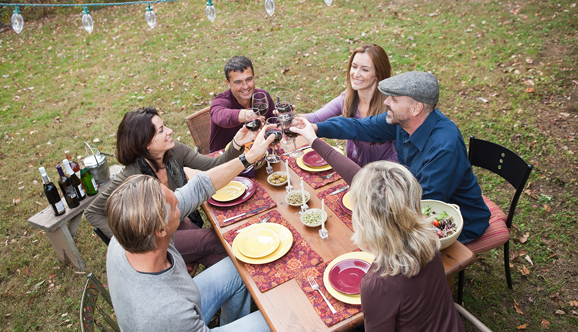 Grupo de amigos celebrando y comiendo en una mesa al aire libre