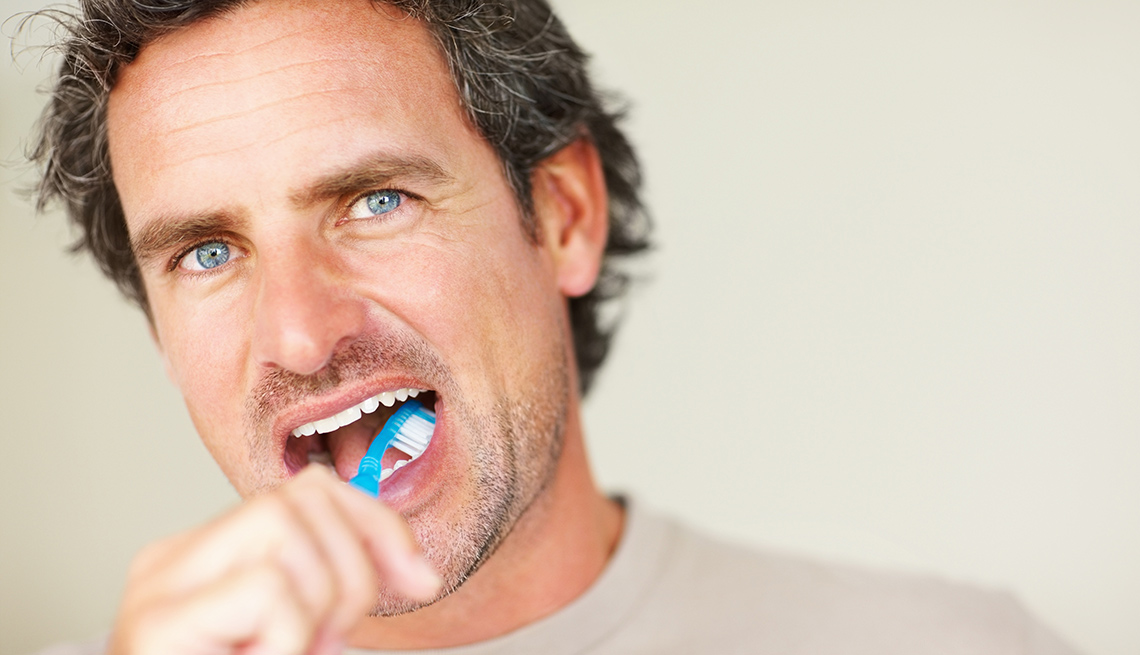 A middle-aged man brushes his teeth
